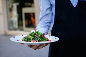 Types de service au restaurant : Un serveur présente un plat à la caméra.